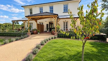 A two-story house with a covered porch, a gravel driveway, and a well-maintained lawn.