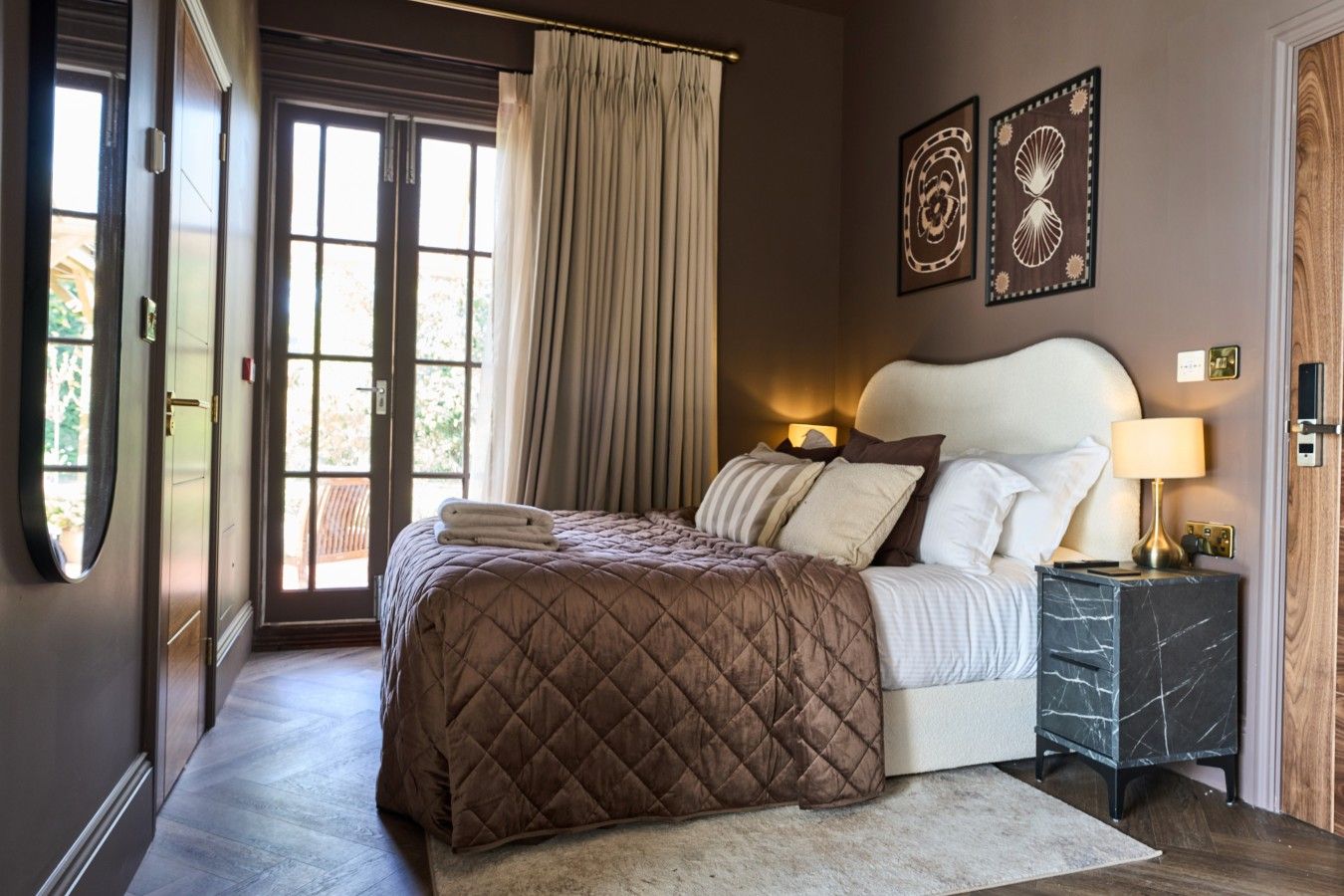 Un dormitorio con una cama, una mesita de noche, una lámpara y una puerta.