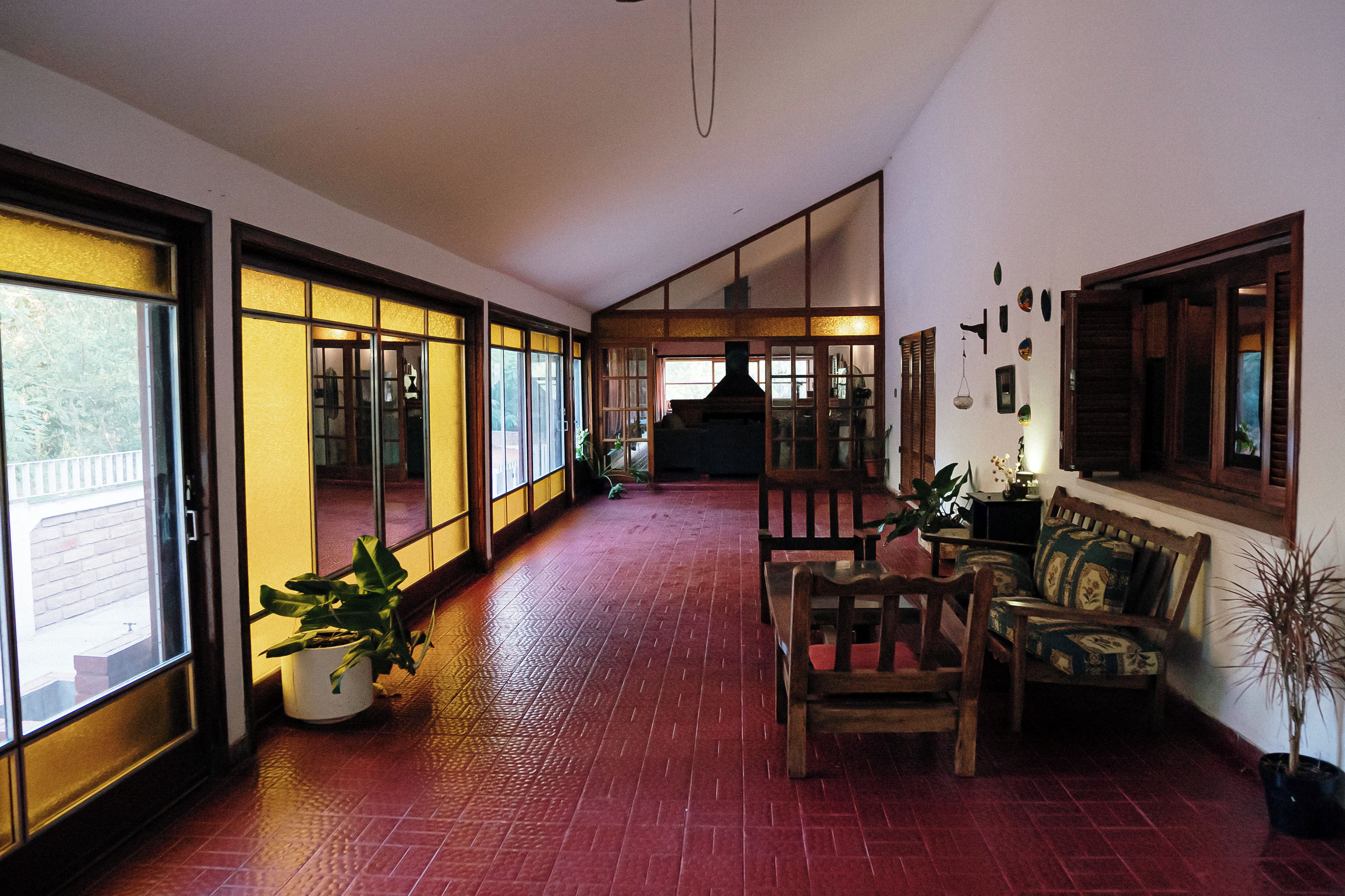 A corridor with sliding glass doors leading to a balcony, a wooden bench, and a table with chairs.
