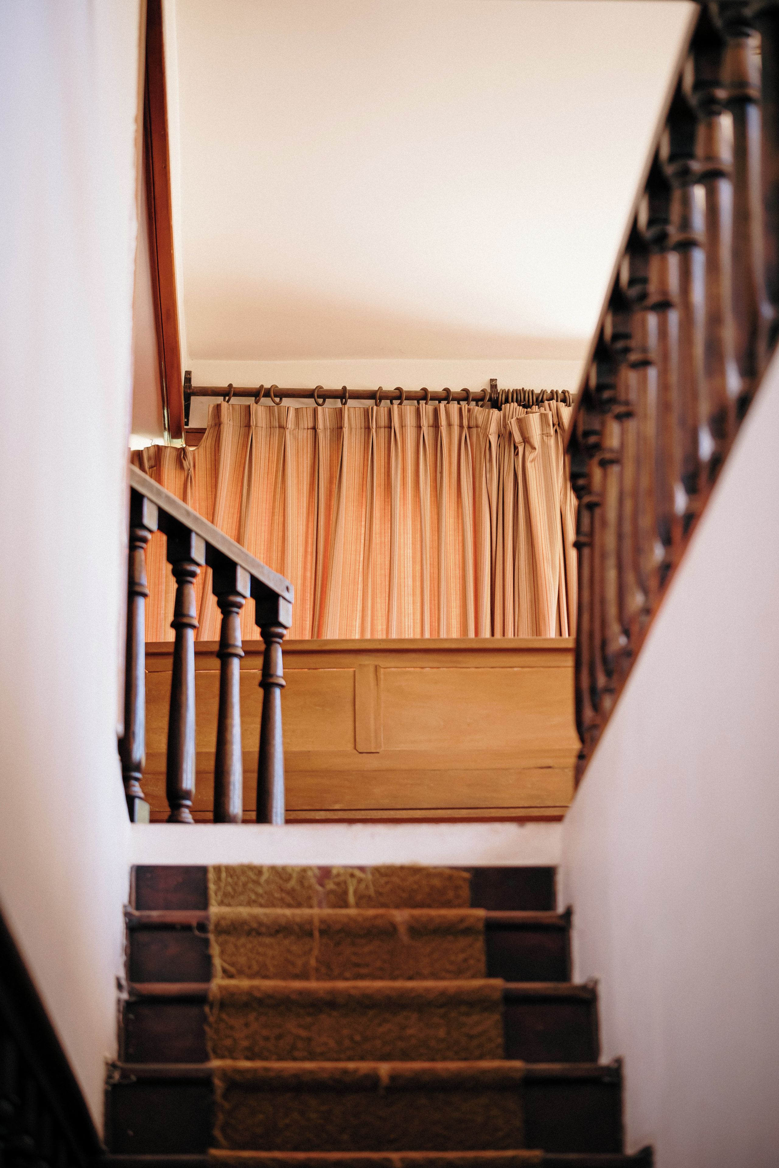 Una scala con balaustre in legno e un pianerottolo rivestito di moquette.