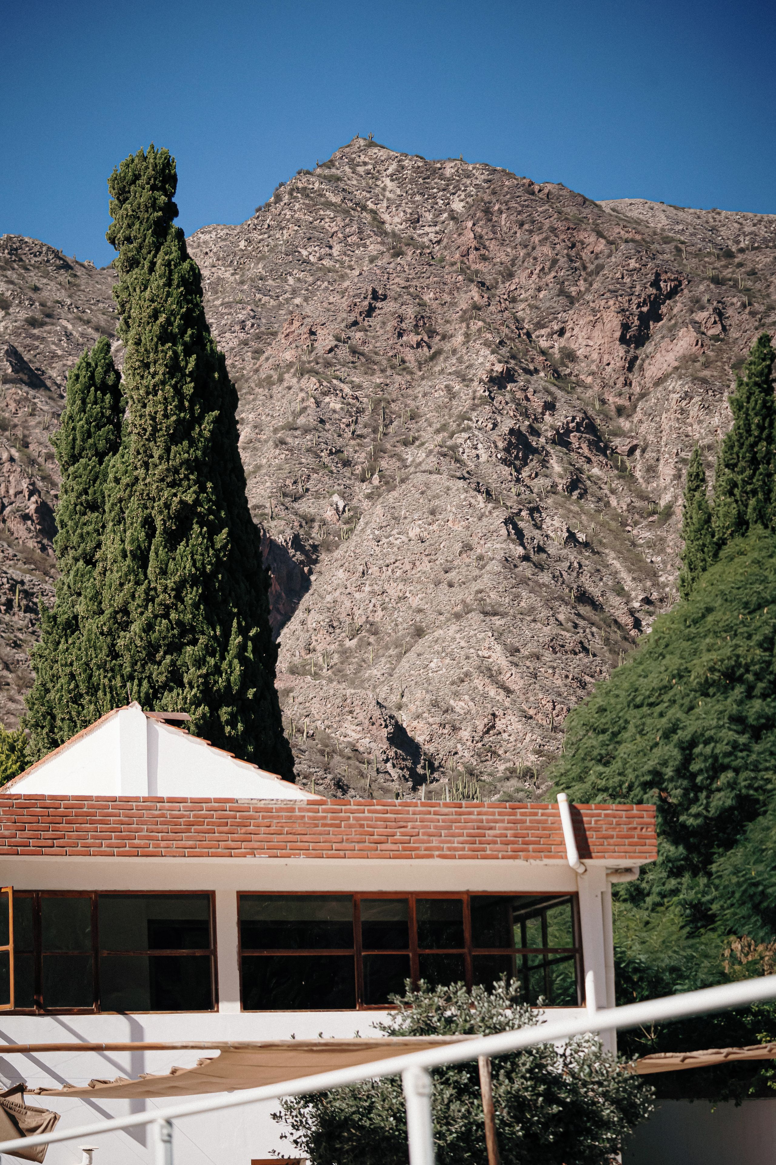 A building with a brick roof and large windows, set against a mountainous backdrop.