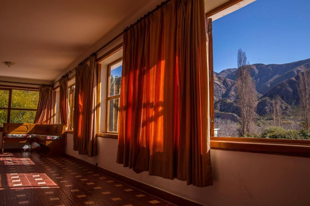 A room with a bed, a window with curtains, and a view of mountains.