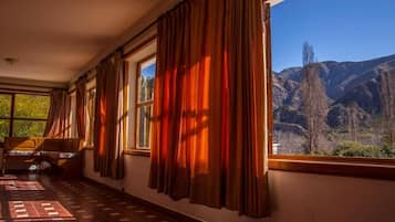 A room with a bed, a window with curtains, and a view of mountains.
