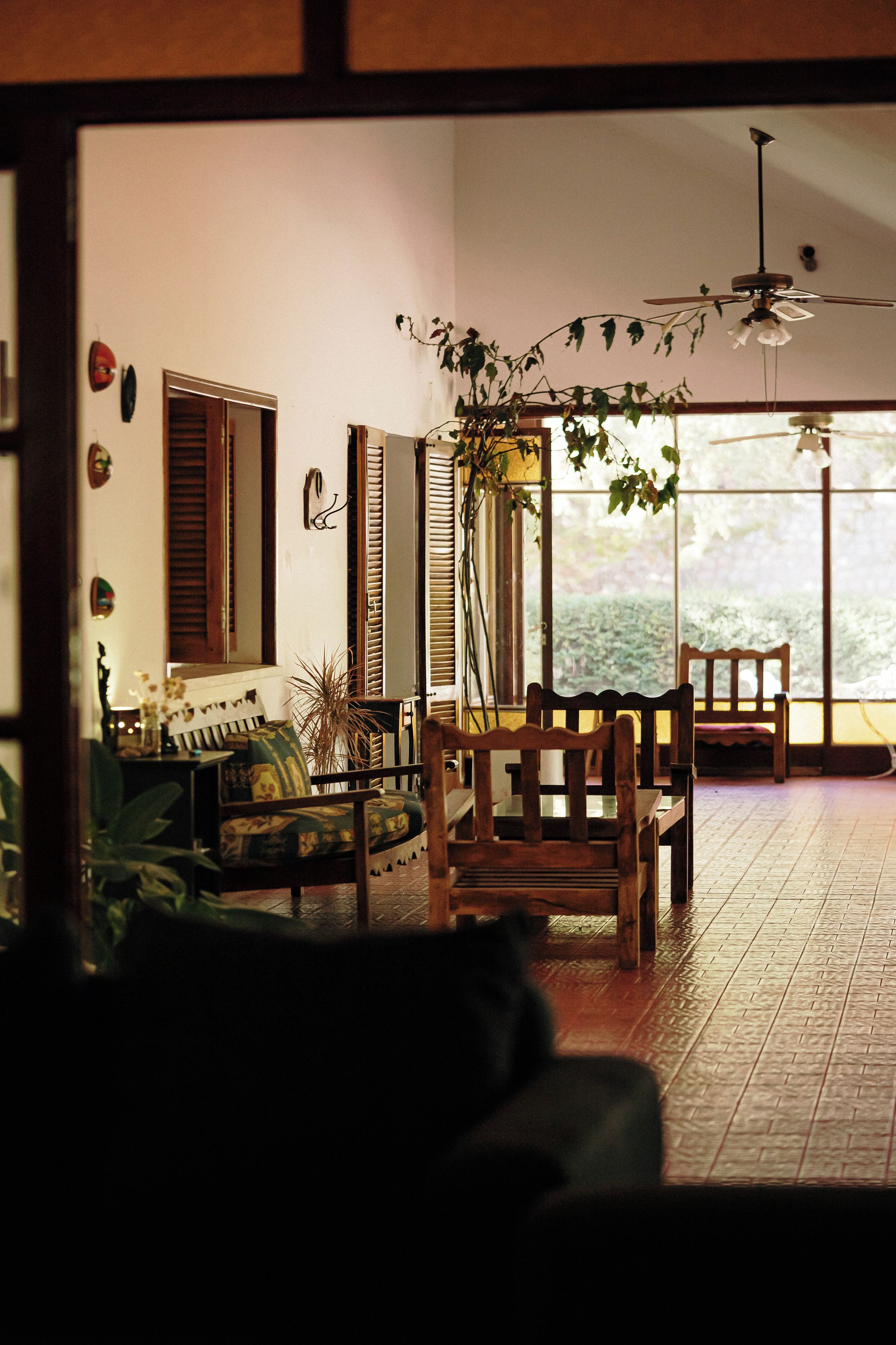 A room with a sofa, a wooden chair, a dining table, and a ceiling fan.