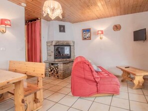 A cozy room with a stone fireplace, wooden furniture, and a red bean bag. - Apartment 'Le Bouvreuil Ouille Du Midi' with Mountain View (Bonneval-sur-Arc)
