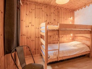 A bunk bed room with wooden walls and a single chair. - Apartment 'Le Bouvreuil Ouille Du Midi' with Mountain View (Bonneval-sur-Arc)