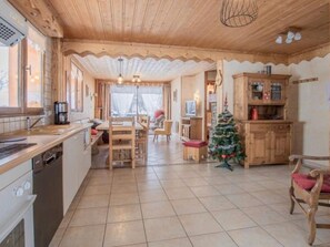 A spacious kitchen with a dining area, a small Christmas tree, and wooden cabinetry. - Apartment 'L'Aigle Chalet Ouille Du Midi' with Mountain View (Bonneval-sur-Arc)
