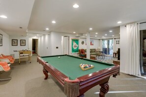 A pool table with a green felt surface, a foosball table, and a seating area with orange chairs. - River Hutte – Hot Tub, Pool Table & River Front (Mount Hood Village)