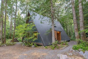Eine Hütte mit schrägem Dach, umgeben von einem Wald.