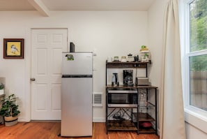 A compact kitchen with a refrigerator, microwave, coffee maker, and a small shelf with jars. - Mt Hood Hygge- A Cozy Tiny Cabin with Hot Tub (Mount Hood Village)