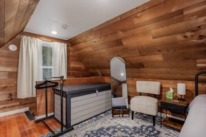 A wooden-paneled room with a bed, a chair, a small table, and a mirror.