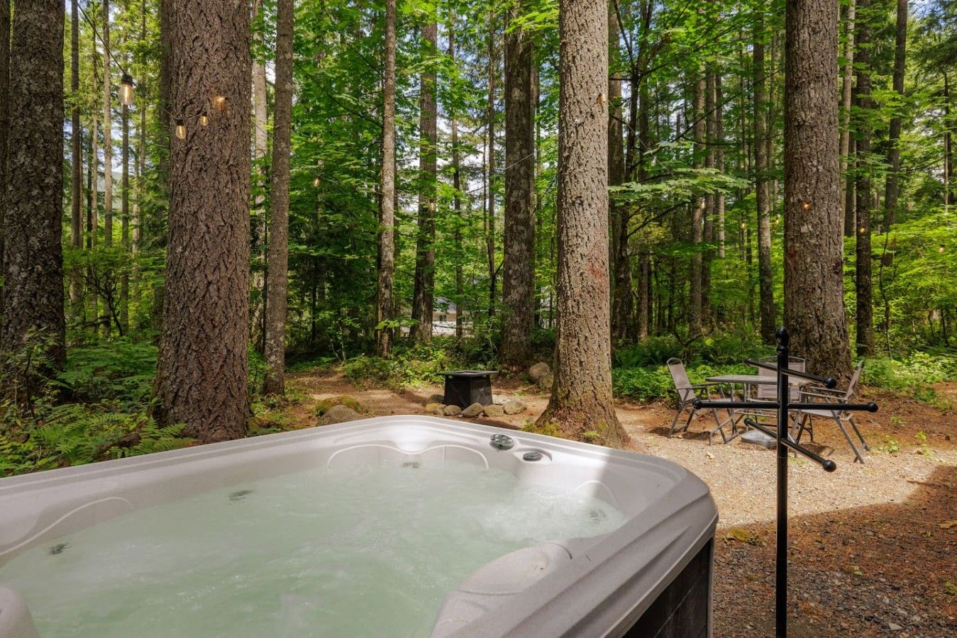 A forest with a hot tub and outdoor seating.