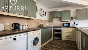 A kitchen with green cabinets, a Bosch washing machine, an oven, and a microwave.