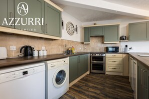 A kitchen with green cabinets, a Bosch washing machine, an oven, and a microwave. - 3BR Flat in Workington | Free Parking | Central Location (Cumberland)