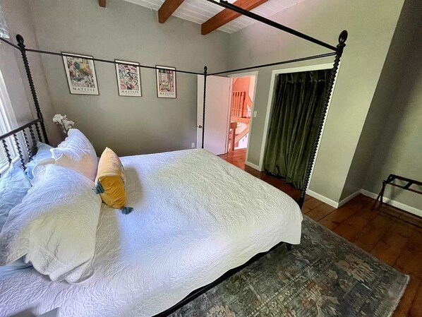 Un dormitorio con cama con dosel, un ventanal grande y obras de arte en la pared.