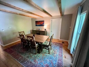 Un comedor con una mesa y sillas de madera, una alfombra y un cuadro en la pared.