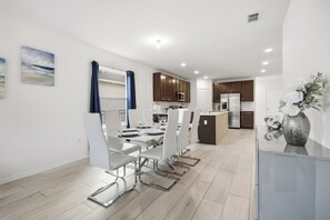 A modern kitchen with wooden cabinets, a built-in microwave, and a refrigerator. - Near Disney 4BR Family Home with Super Mario Room (Kissimmee)