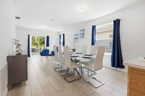 Een moderne eetruimte met een lange tafel, witte stoelen en uitzicht op de omgeving.