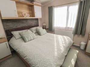 A bedroom with a bed, bedside tables, a nightstand, a lamp, a window with curtains, and a wooden headboard. - 19 Finch (Scarborough)