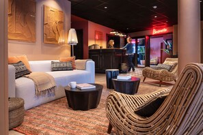 A lobby with a sofa, chairs, a coffee table, and a reception desk. - Skis aux pieds | Sauna privatif | Accès piscine (Tignes)