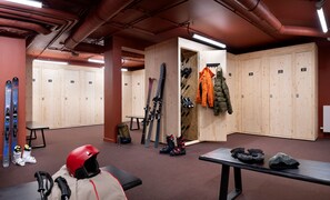 A ski locker room with wooden lockers, benches, and ski equipment. - Skis aux pieds | Sauna privatif | Accès piscine (Tignes)