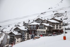A multi-story hotel with a ski lift in the background, surrounded by snow-covered mountains. - Au pied des pistes | Piscine | Esprit famille (Val Thorens)