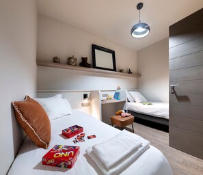 Een hotelkamer met een bed, nachtkastje en een plank met decoratieve spullen.