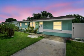 A single-story mobile home with a front porch, a small front yard, and a driveway leading to the entrance. - Modern 3BR Pool Home · 15 Min to Beaches (Pinellas Park)