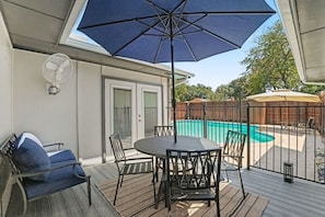 Eine überdachte Terrasse im Freien mit Pool, Tisch und Stühlen.