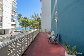 A balcony with a red floor, white railing, and two chairs. - Beachfront Cozy Loft  Walk 2 Eat Isla Verde Beach (Carolina)