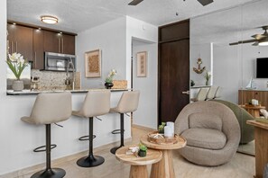 A modern kitchen with a microwave, bar stools, and a dining area with a round table and a large armchair. - Beachfront Cozy Loft  Walk 2 Eat Isla Verde Beach (Carolina)