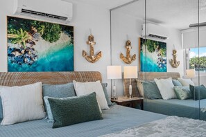 Een slaapkamer met een groot bed, twee nachtkastjes, een spiegel en kunstwerken.