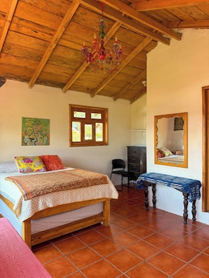 Un dormitorio con cama de madera, un escritorio, una silla, un espejo y una araña.