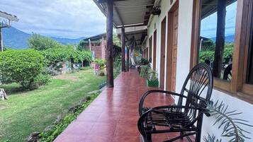 A covered outdoor area with a bench, potted plants, and a view of a mountainous landscape.