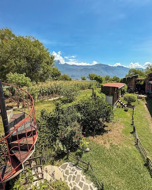 A vineyard with a spiral staircase, a small building, and mountains in the background. - Luna y Sol Atitlan (San Pedro La Laguna)