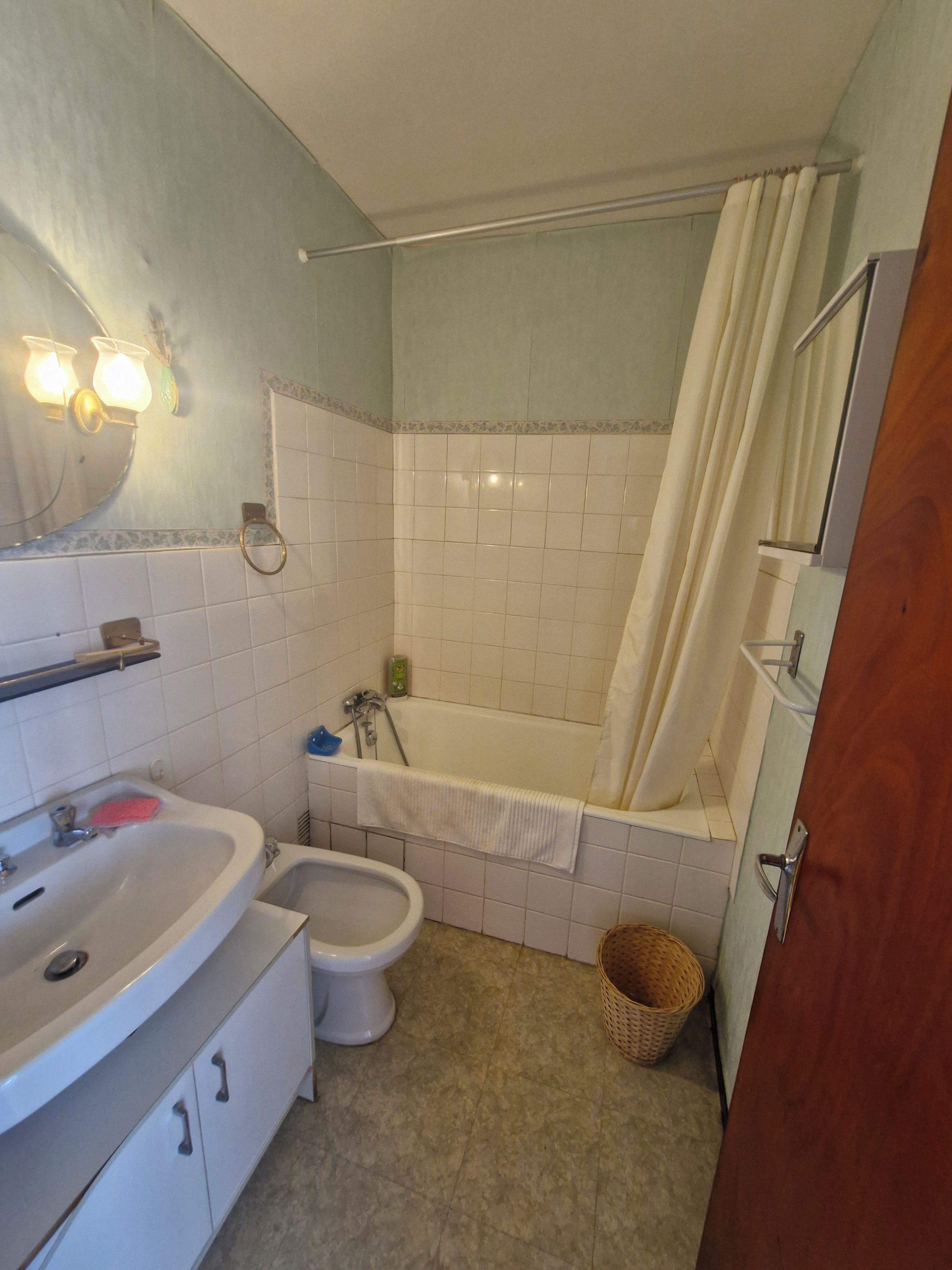 A bathroom with a bathtub, a sink, a bidet, and a mirror.