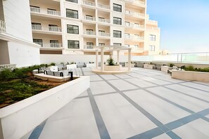 A multi-story hotel with a rooftop terrace featuring seating areas, a central garden, and a pergola. - 2BR + Huge Private Terracen- Al Furjan Near Metro (Dubai)