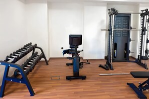 A gym with exercise equipment, including dumbbells, a stationary bike, and a weight machine. - 2BR + Huge Private Terracen- Al Furjan Near Metro (Dubai)