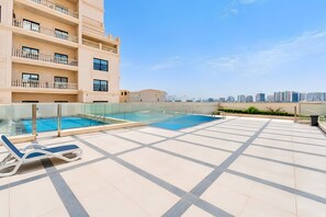 A rooftop swimming pool with lounge chairs, a clear sky, and high-rise buildings in the background. - 2BR + Huge Private Terracen- Al Furjan Near Metro (Dubai)