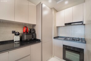 A modern kitchen with a built-in oven, a coffee maker, and a microwave. - 2BR + Huge Private Terracen- Al Furjan Near Metro (Dubai)