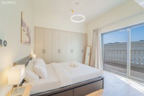 A hotel room with a bed, bedside table, lamp, wardrobe, and a view of the outside. - 2BR + Huge Private Terracen- Al Furjan Near Metro (Dubai)