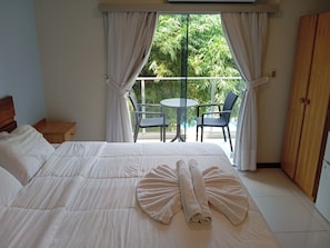 Una camera d'albergo con un letto, un balcone con tavolo e sedie, e un armadio.