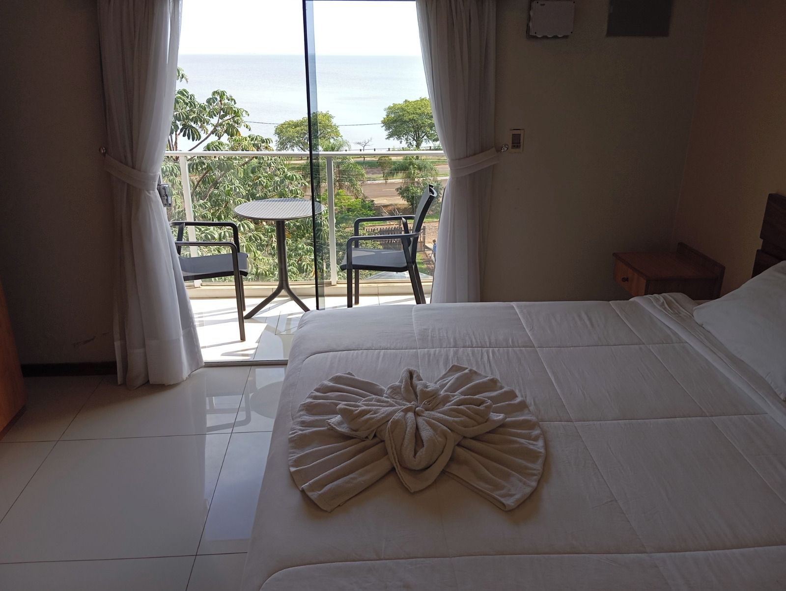 Habitación de hotel con cama, una mesa, sillas y vista al mar.