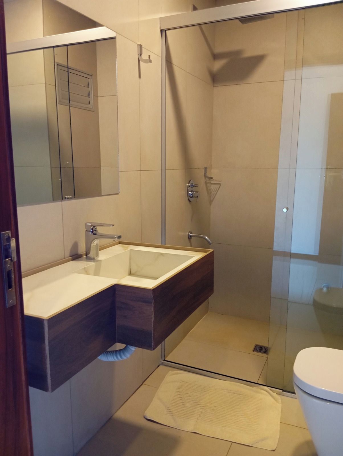 A modern bathroom with a glass shower enclosure, a vanity with a sink, and a toilet.