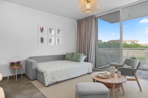A modern living room with a grey sofa, a small round table, and a balcony with a view. - New: 2-Bedroom Family Apartment | Blu Horizon | Pool (Paralimni)