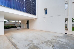 A modern building with a flat roof, solar panels, and a concrete courtyard. - New: 2-Bedroom Family Apartment | Blu Horizon | Pool (Paralimni)