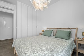 Ein Schlafzimmer mit einem Bett, einem Nachttisch, einer Nachttischlampe, einem Kleiderschrank und einer Deckenleuchte.