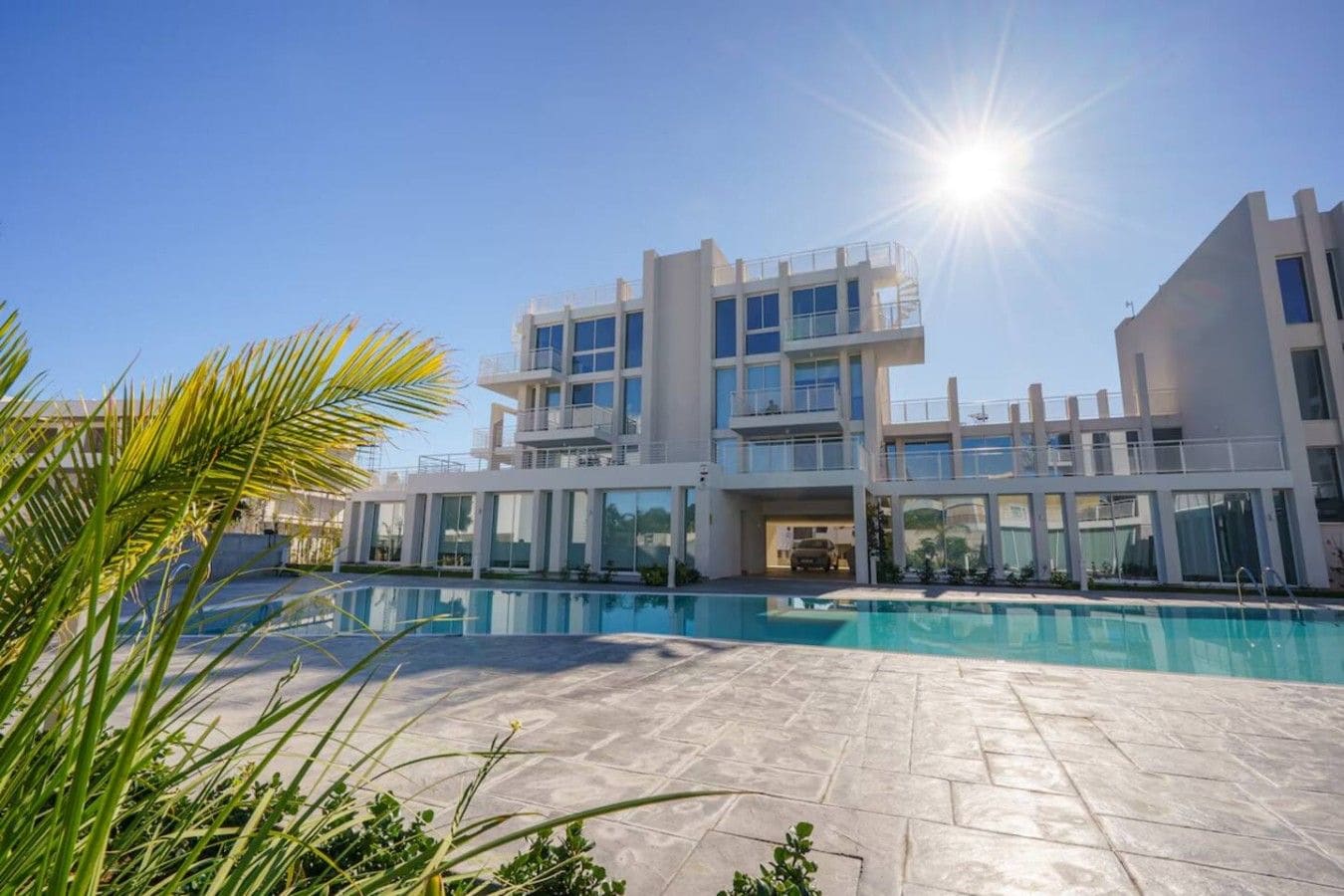 A modern multi-story building with a swimming pool in front.