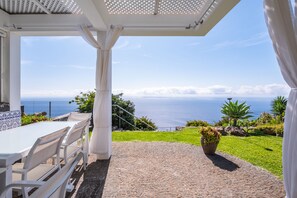 A covered outdoor seating area with a view of the sea. - Vrbo Property (Fajã da Ovelha)