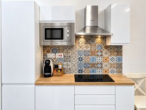 Cozinha equipada com micro-ondas, cafeteira e painel decorativo.